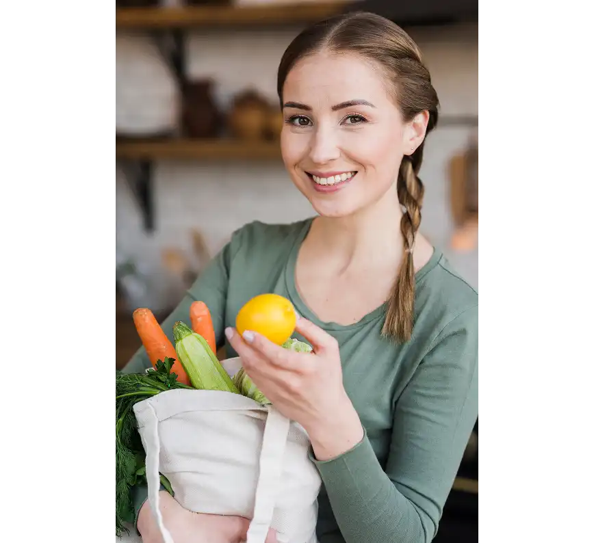 Smiling woman holding a reusable grocery bag filled with fresh vegetables and fruits